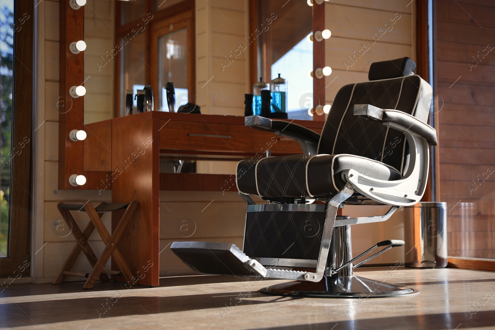 Photo of Stylish hairdresser's workplace with professional armchair and large mirror in barbershop. Interior design