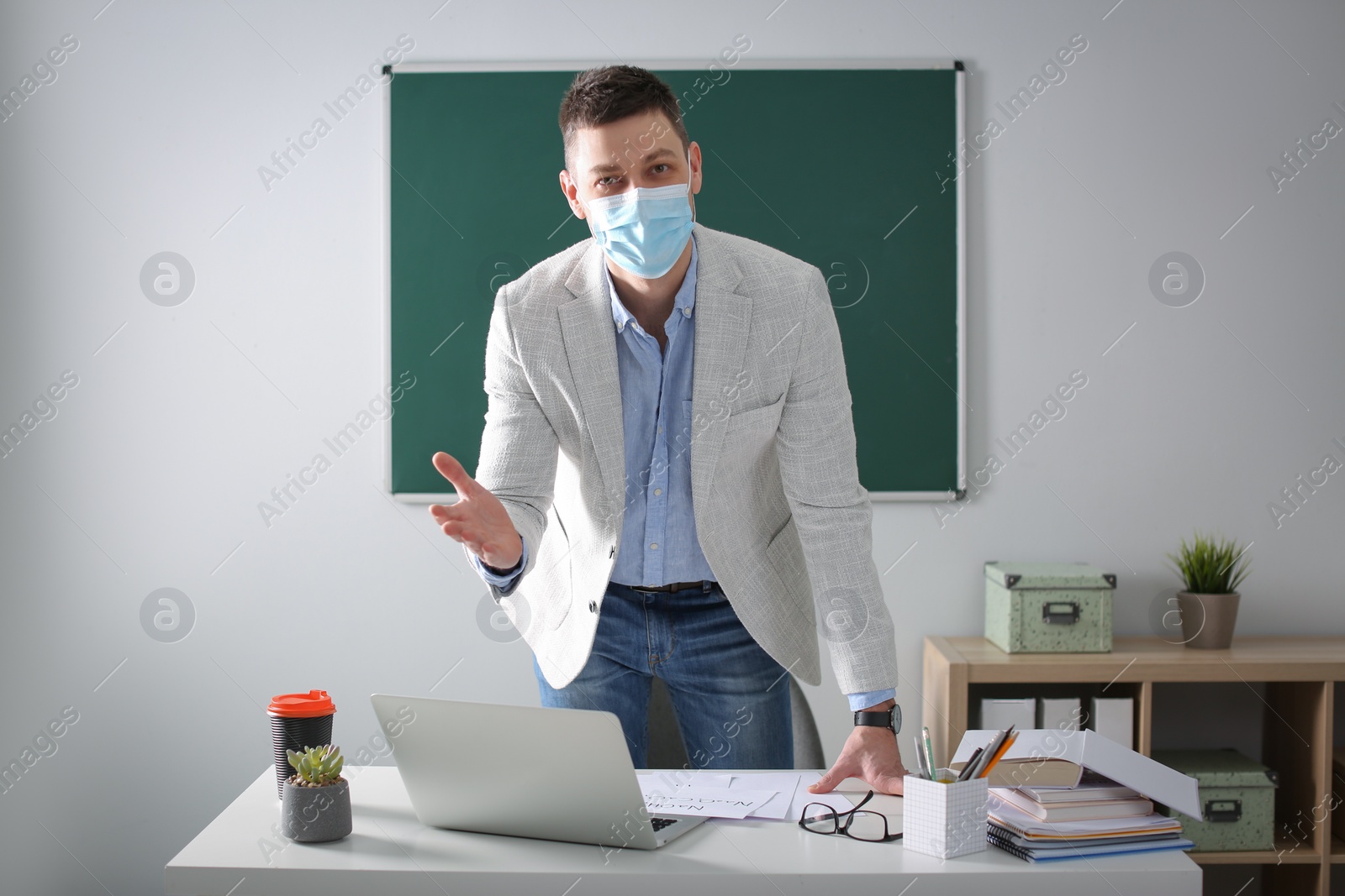 Photo of Teacher with protective mask conducting lesson in classroom. Reopening after Covid-19 quarantine