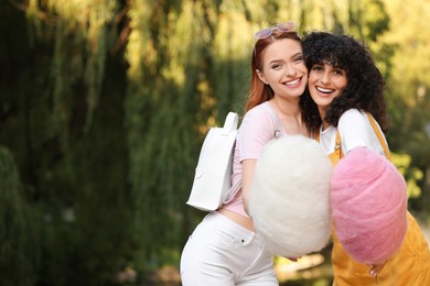 Photo of Happy friends with cotton candies in park on sunny day. Space for text