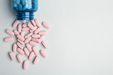 Photo of Vitamin pills and bottle on grey background, top view. Space for text