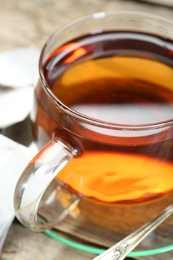 Aromatic tea in glass cup on wooden table, closeup