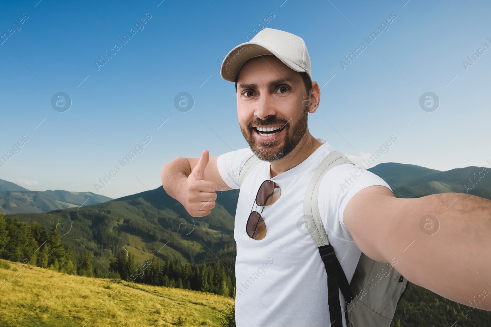 Image of Smiling man taking selfie and showing thumbs up in mountains