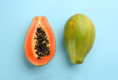 Fresh ripe papaya fruits on light blue background, flat lay