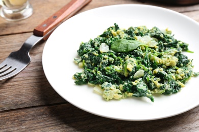 Photo of Tasty cooked spinach served on wooden table, closeup. Healthy food