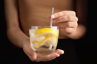 Photo of Woman holding glass of soda water with lemon slices and ice cubes, closeup