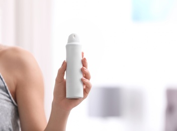 Photo of Beautiful young woman holding deodorant in room, closeup. Space for text