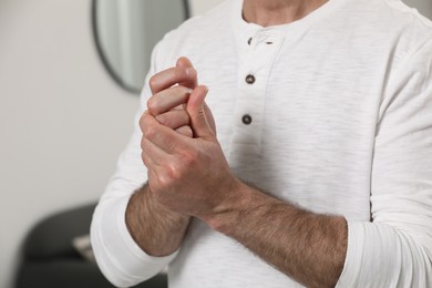 Man cracking his knuckles on blurred background, closeup. Bad habit