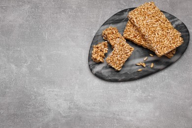 Photo of Board with puffed rice bars (kozinaki) on grey table, above view. Space for text