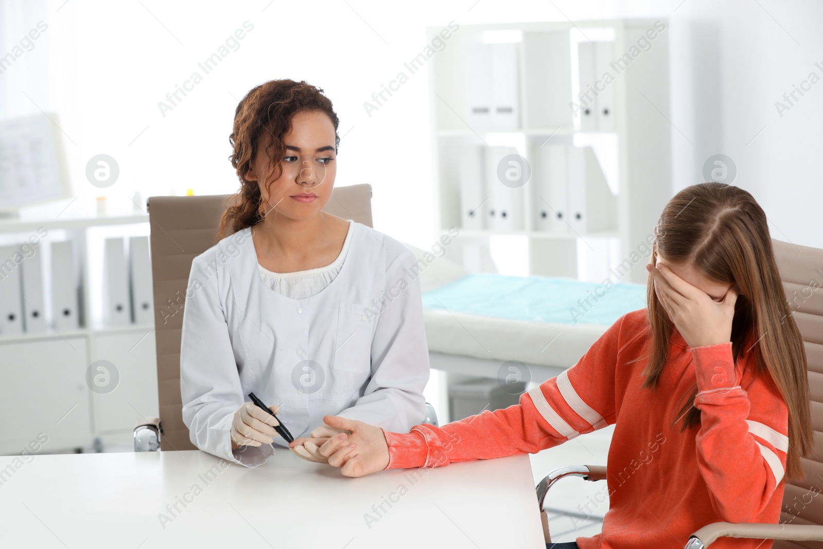 Photo of Doctor taking patient's blood sample with lancet pen in hospital. Diabetes control