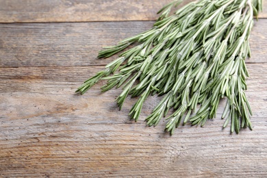 Photo of Fresh rosemary twigs on wooden table