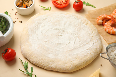 Photo of Dough and fresh ingredients for seafood pizza on beige background