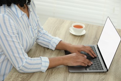 Photo of Woman using laptop at wooden desk indoors, closeup