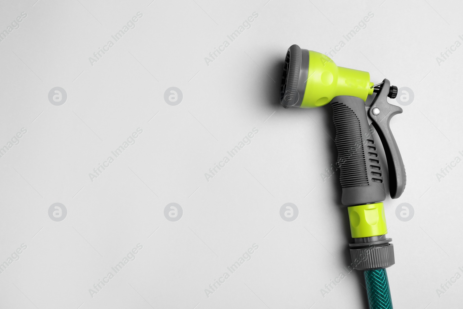 Photo of Watering hose with sprinkler on light grey background. Space for text