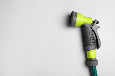 Watering hose with sprinkler on light grey background. Space for text