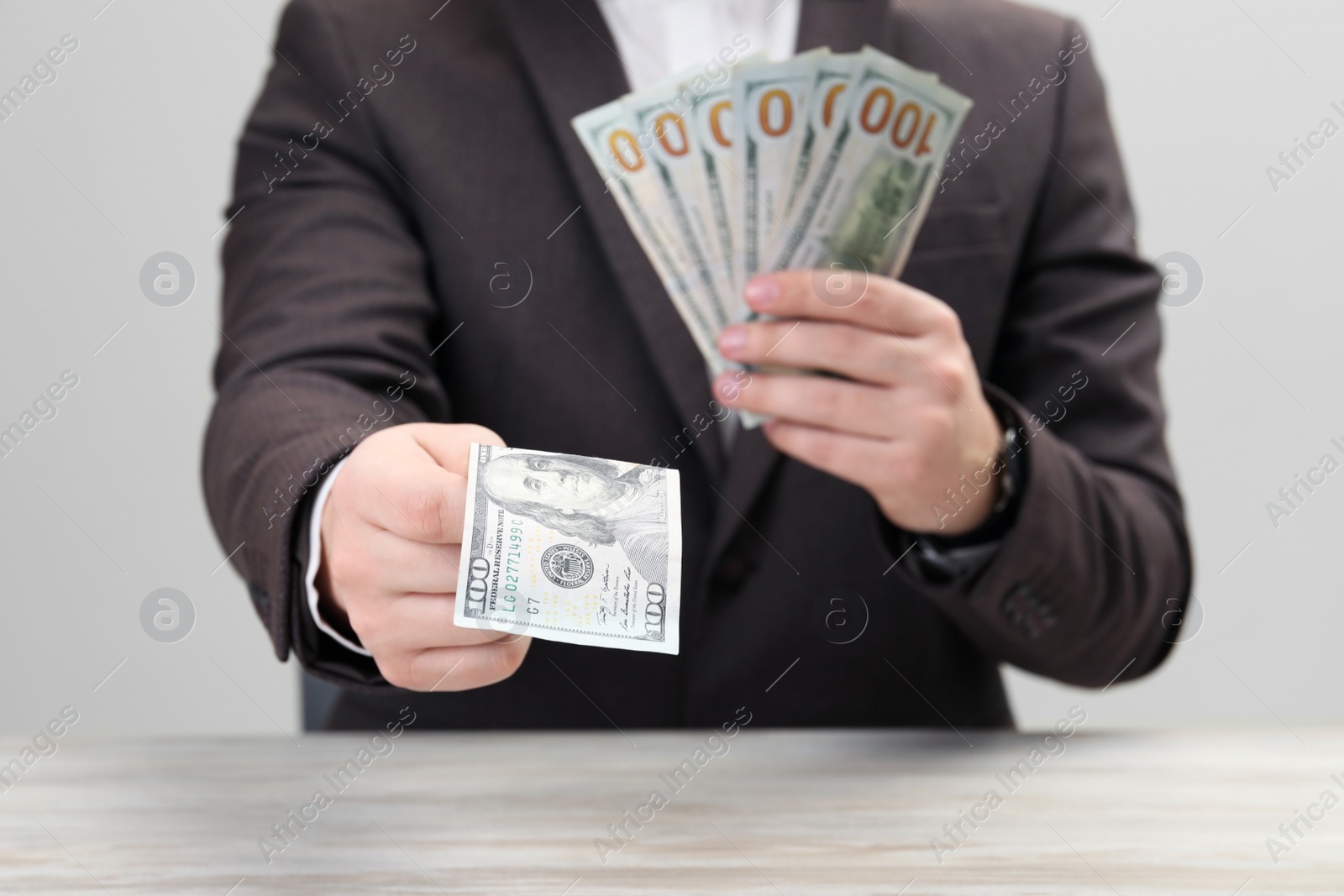 Photo of Man holding money at white wooden table, closeup. Currency exchange