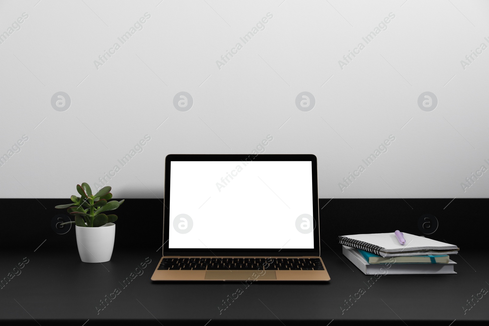 Photo of Modern laptop with blank screen on black table. Mockup for design
