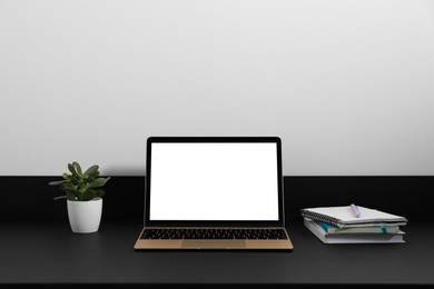 Modern laptop with blank screen on black table. Mockup for design