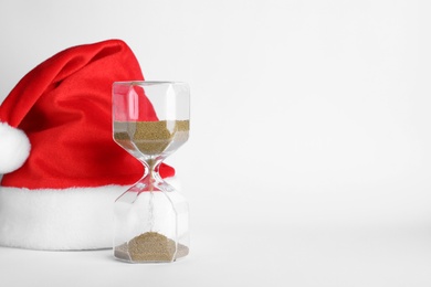 Photo of Hourglass and Santa hat on white background. Christmas countdown