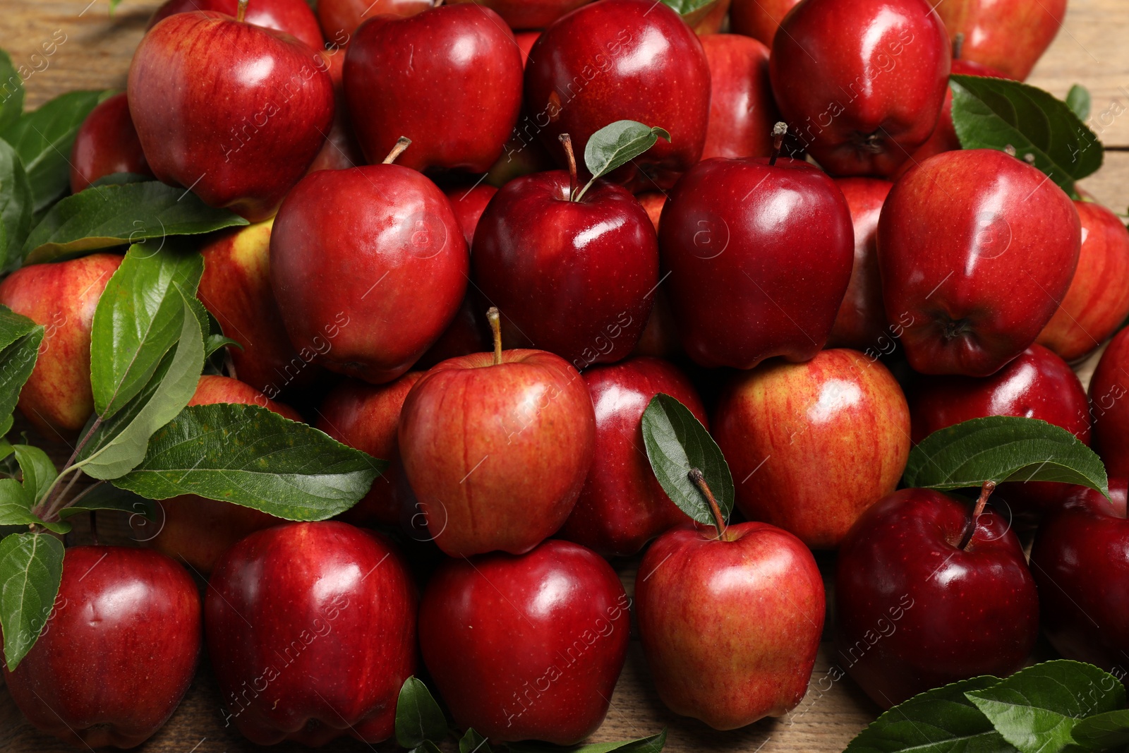 Photo of Fresh ripe red apples with leaves on wooden table, flat lay