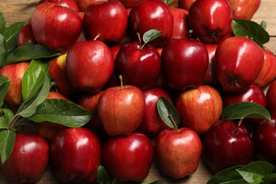 Fresh ripe red apples with leaves on wooden table, flat lay