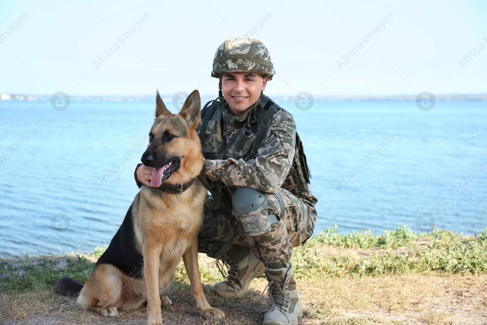 Photo of Man in military uniform with German shepherd dog near river