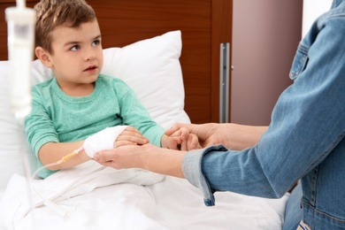 Photo of Woman visiting her little child with intravenous drip in hospital