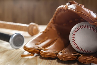 Photo of Baseball glove and ball on wooden table, closeup