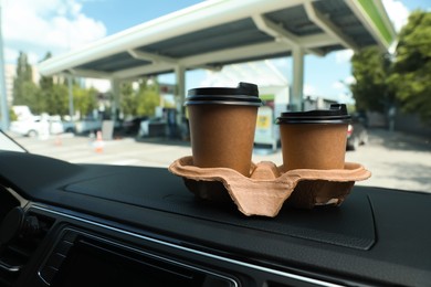 Photo of Paper coffee cups on car dashboard at gas station. Space for text