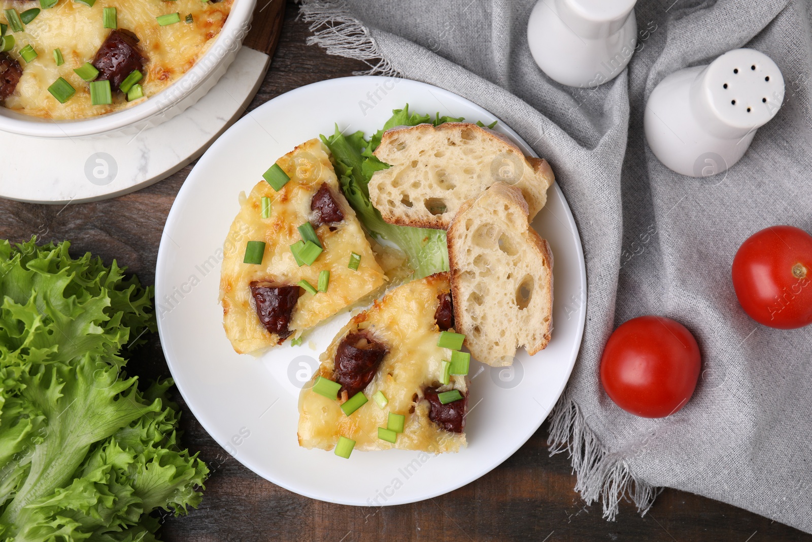 Photo of Tasty sausage casserole with green onion served on wooden table, flat lay