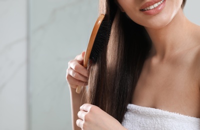 Young woman with hair brush in bathroom, closeup view