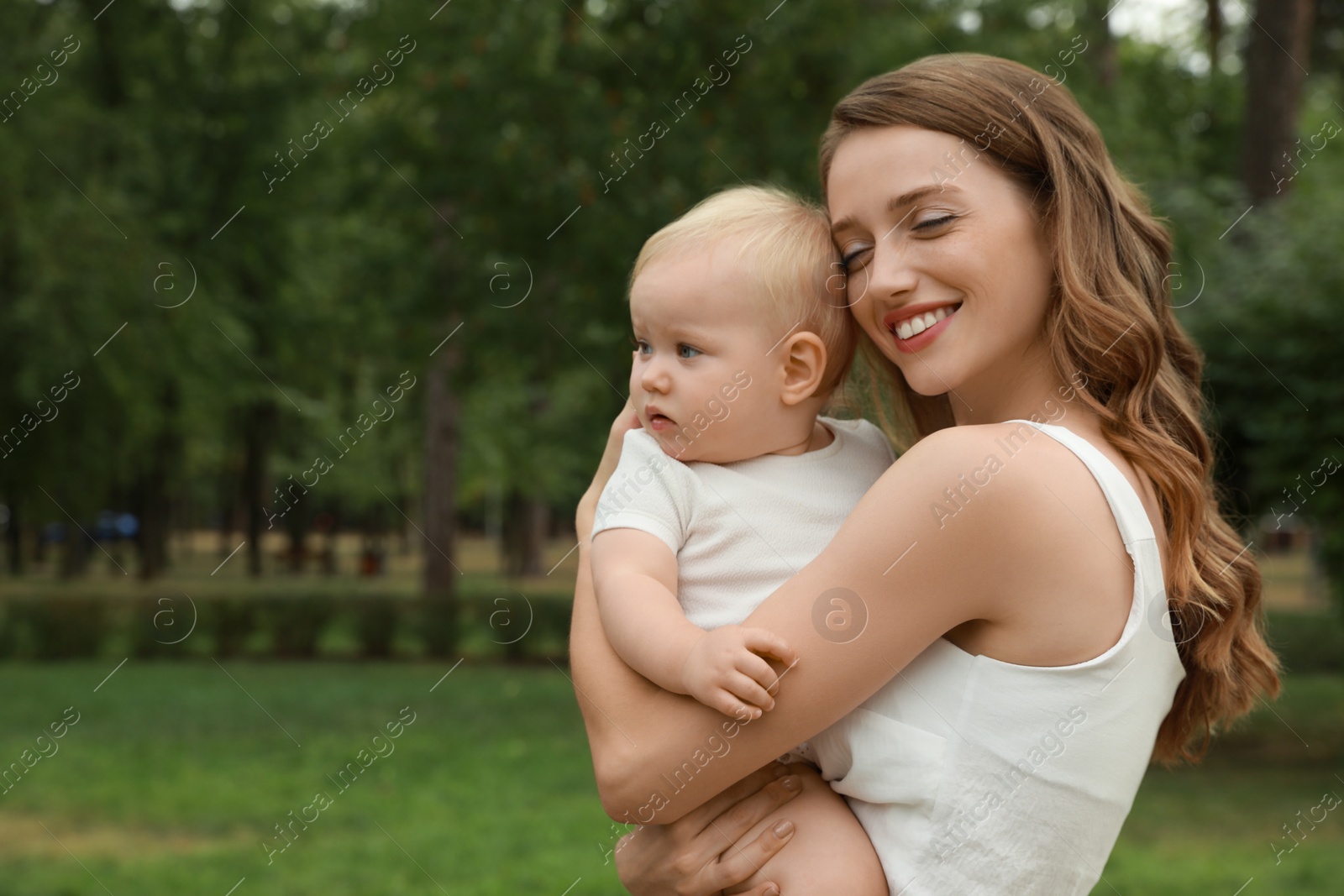 Photo of Mother with her cute baby spending time together outdoors. Space for text