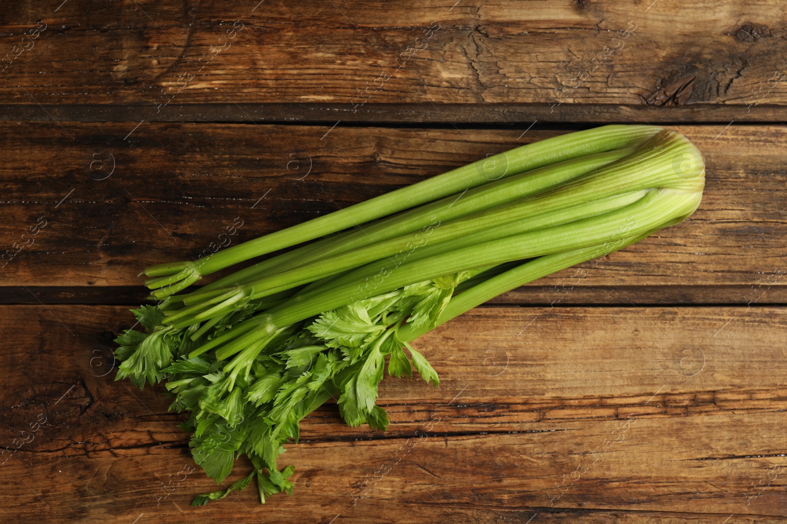 Photo of Fresh ripe green celery on wooden table, top view