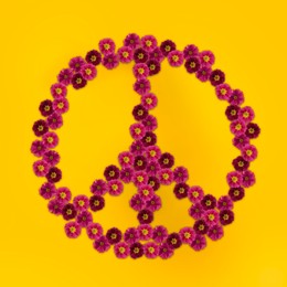 Image of Hippie peace symbol made of primula flowers on yellow background