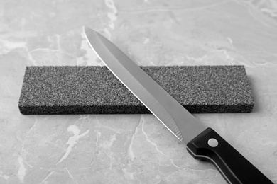 Photo of Knife and sharpening stone on grey background