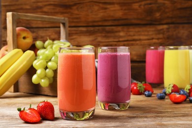 Photo of Glasses with different tasty smoothies and ingredients on wooden table