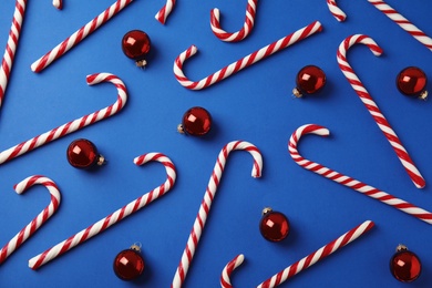 Photo of Flat lay composition with candy canes and Christmas balls on blue background