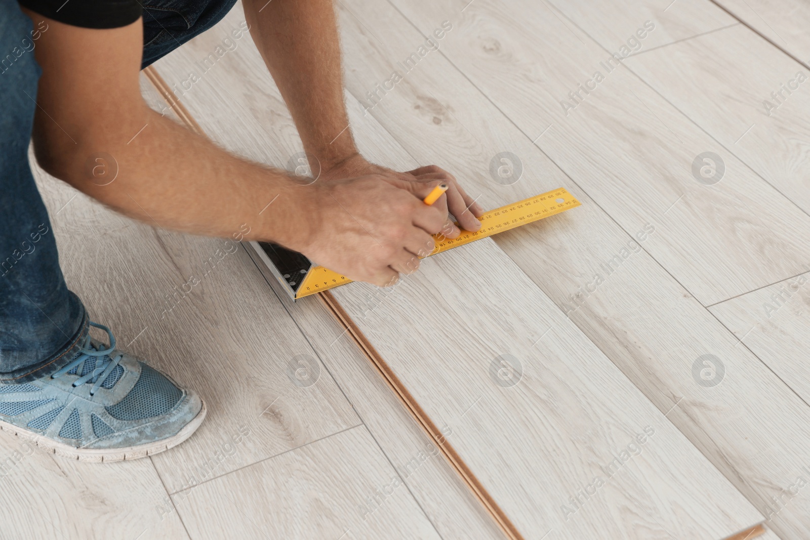 Photo of Worker installing new laminate flooring in room, closeup