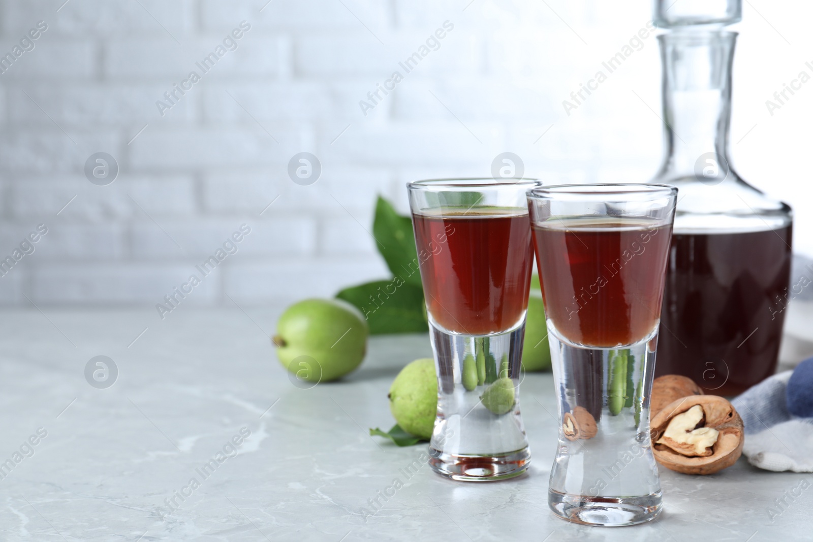 Photo of Delicious liqueur and fresh walnuts on light grey table. Space for text