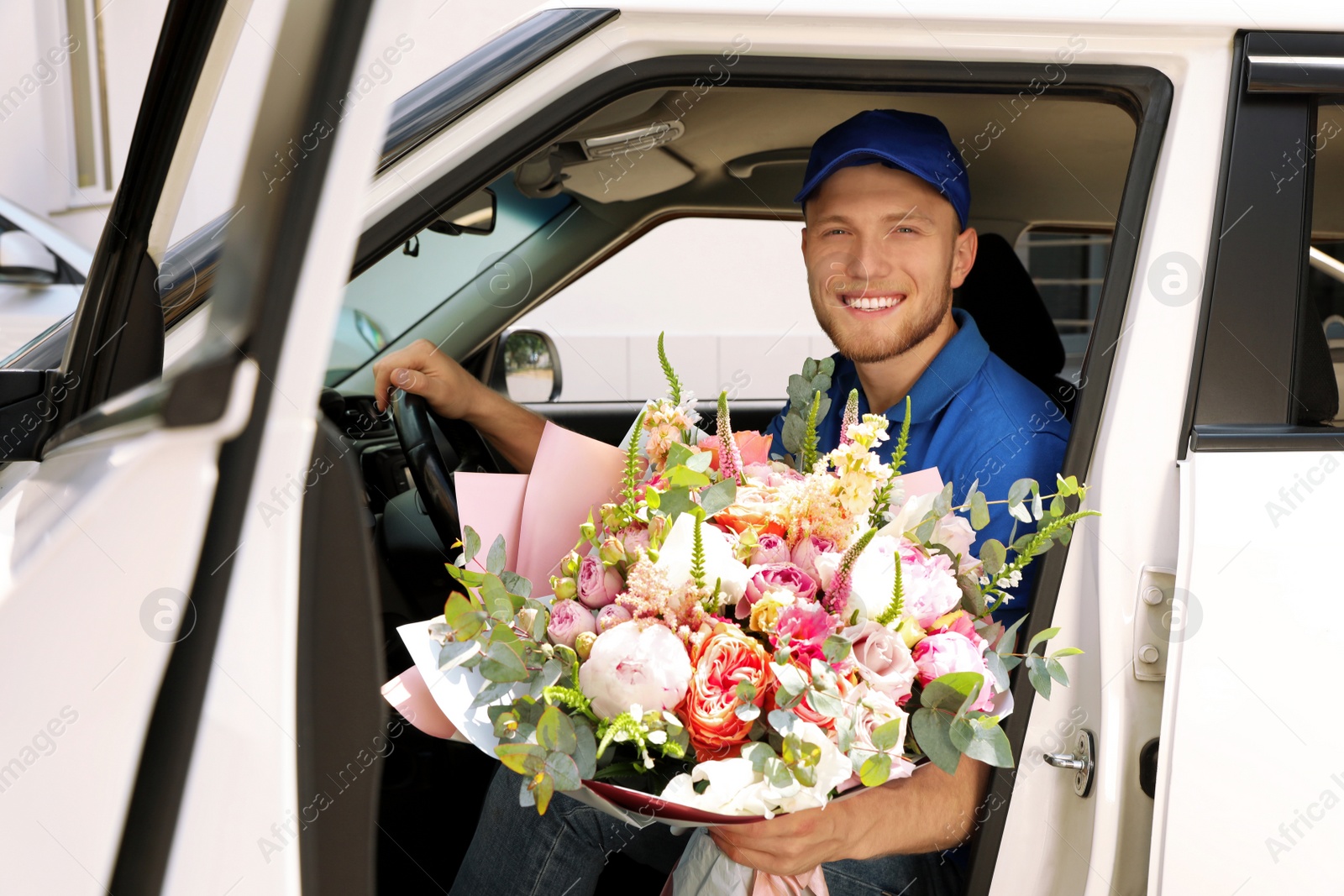 Photo of Delivery man with beautiful flower bouquet sitting in car