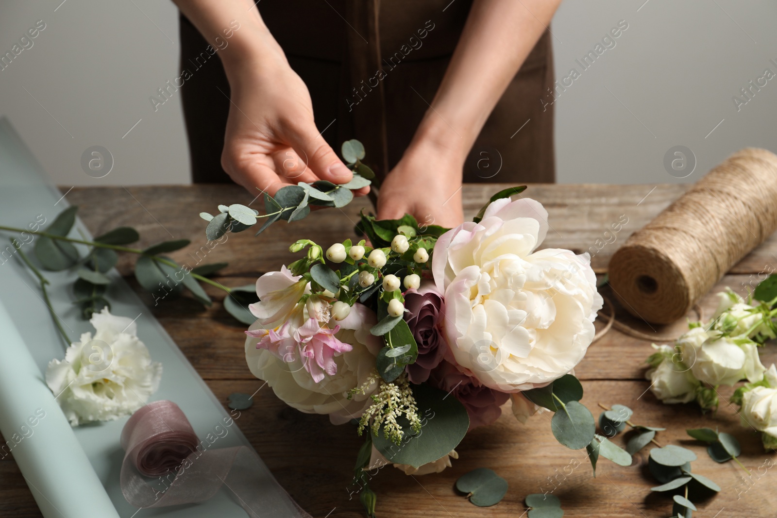 Photo of Florist creating beautiful bouquet at wooden table indoors, closeup