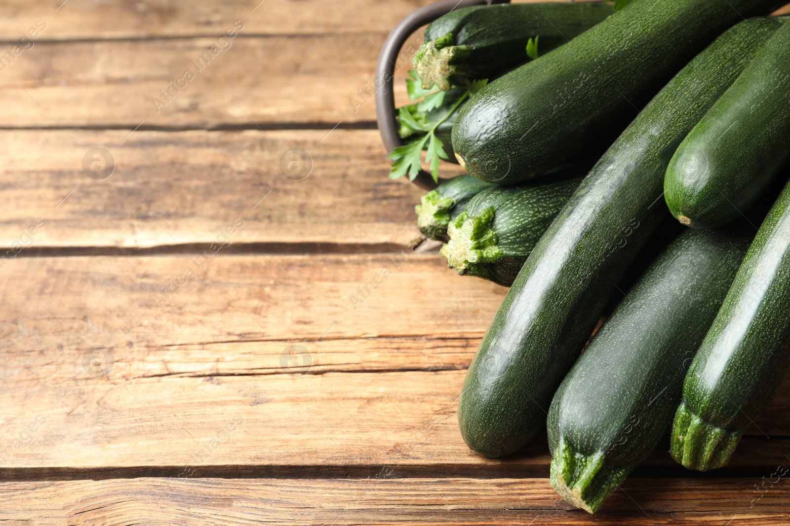 Photo of Green zucchinis on wooden table, closeup. Space for text