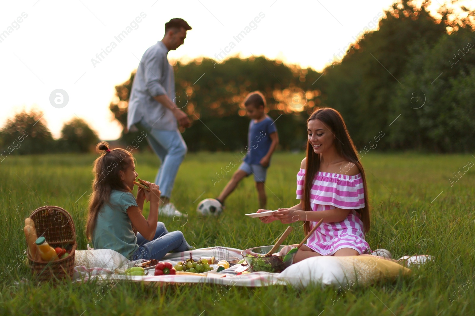 Photo of Happy family having picnic in park at sunset