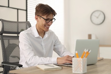 Photo of Man watching webinar at wooden table in office