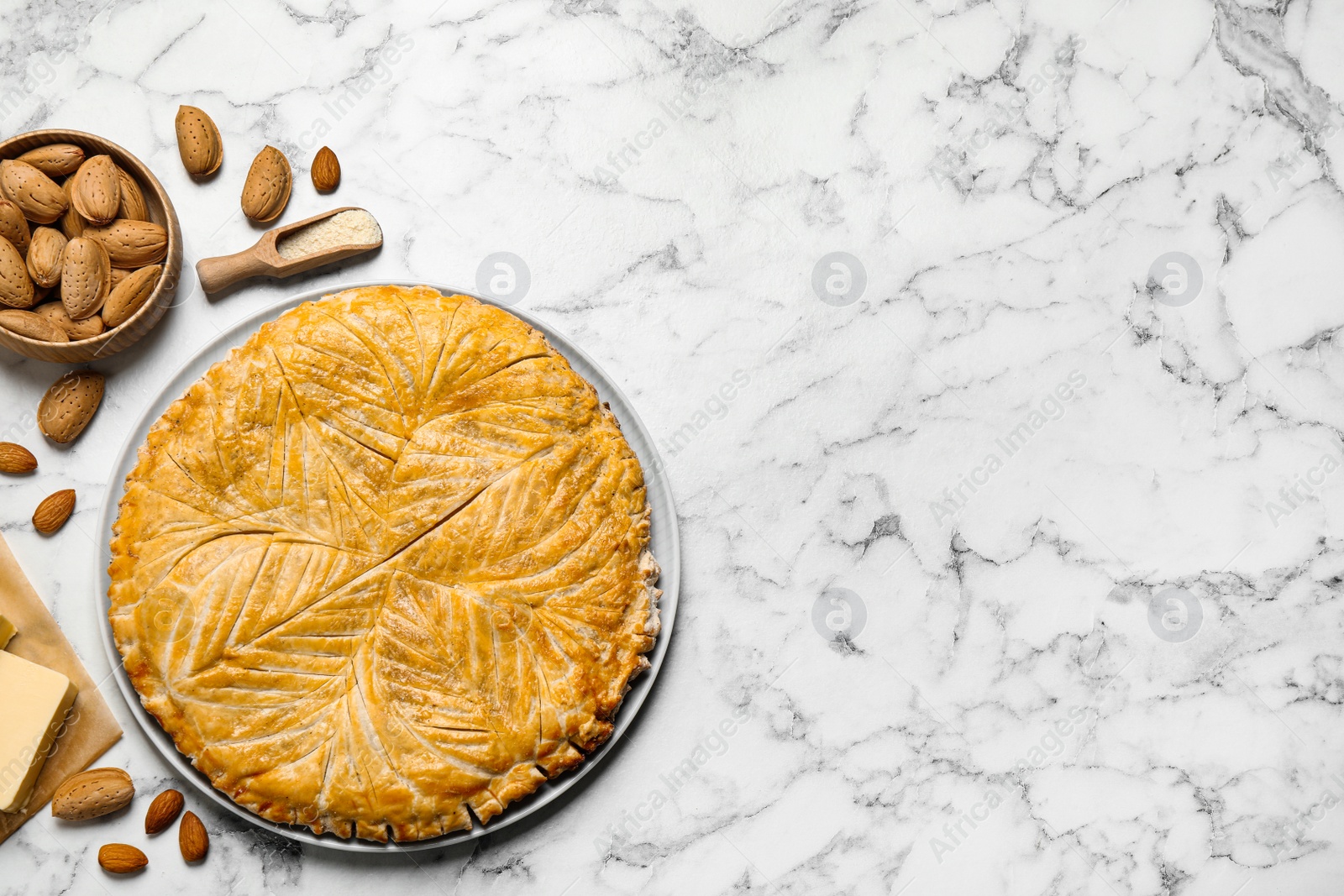 Photo of Traditional galette des rois and ingredients on white marble table, flat lay. Space for text