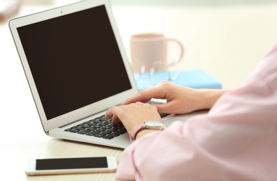 Young woman using laptop at table indoors, closeup with space for text