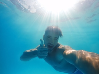 Handsome young man swimming in pool, underwater view