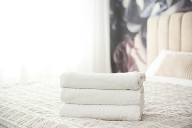 Photo of Clean white towels on bed at home