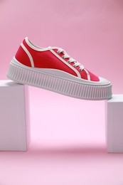 Photo of Stylish presentation of red classic old school sneaker on pink background