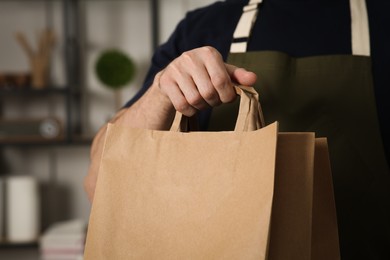 Worker with paper bags indoors, closeup view