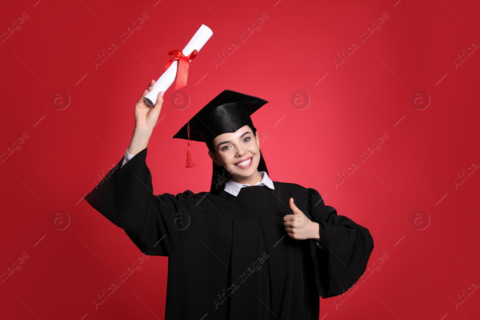 Photo of Happy student with graduation hat and diploma on red background